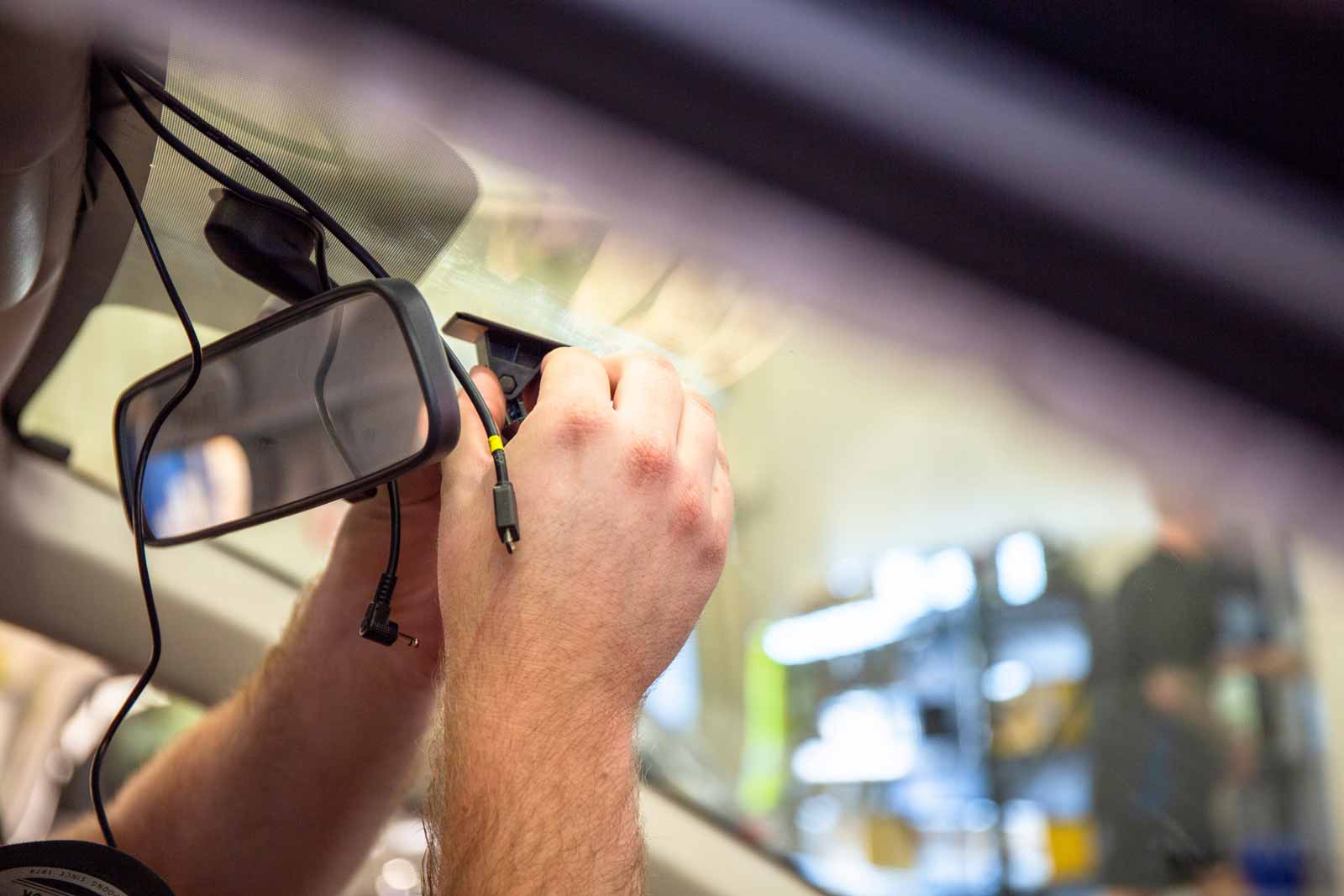 Technician from Hear Me Coming Audio installing a front-facing camera on vehicle's dashboard